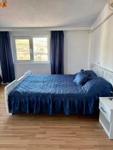 Un dormitorio con una cama con edredón azul y dos ventanas. en Apartment Park View, en Sandanski