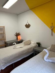 Habitación con 2 camas y pared amarilla y blanca. en Roomin Hostel, en Salamanca
