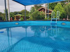 a blue swimming pool with a chair in the water at Abenteuer für die ganze Familie - Großzügiges Haus im ZenGarden Paraguay in San Lorenzo de la Frontera