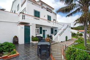 a white house with a patio with a table at Bungalow Country House Private in Caniço