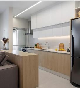 a kitchen with white cabinets and a stainless steel refrigerator at Resort piscina aquecida suíte e churrasqueira in Florianópolis