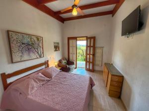 圣罗克迪米纳斯Sons da Canastra Pousada e Terapias - em São José do Barreiro - São Roque de Minas MG的一间卧室，里面有一张床和一台平板电视