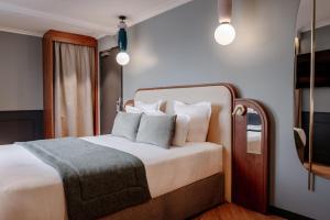 ein Schlafzimmer mit einem Bett mit weißen Laken und Kissen in der Unterkunft Grand Hotel Saint Michel in Paris