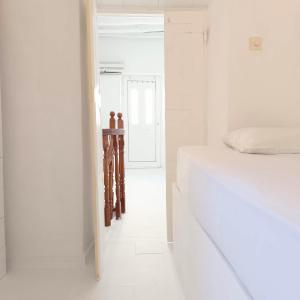 a white bedroom with a bed and a hallway at Perno in Serifos Chora +9 photos