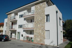 a white apartment building with a stone wall at Gruber Apartman in Siófok