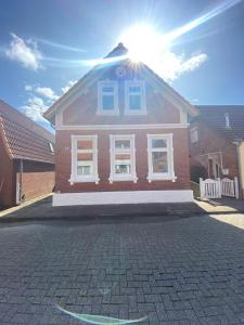 a brick house with the sun shining on the roof at Haus Schönborn Norden Family in Norden