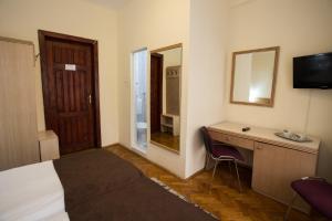 Cette chambre comprend un lit, un bureau et un miroir. dans l'établissement Hotel Rina Cerbul, à Sinaia