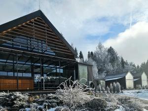 a house in the snow with a building at Lakeforest Dedinky Wellness Chata privát jacuzzi aj sauna, výhľad na jazero in Dedinky