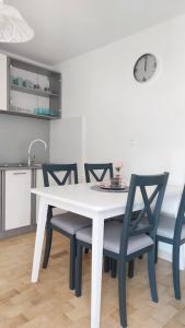 a white table and chairs in a kitchen with a clock at Bravarica blue in Potocnica