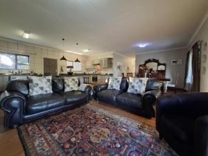 a living room with black leather couches and a rug at Zacks Country Stay Self-catering in Krugersdorp