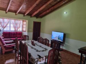 a dining room with a table with chairs and a television at CASA Costanera in Cafayate