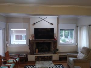 sala de estar con TV de pantalla plana sobre una chimenea en V do Lago Negro - CASA, en Gramado