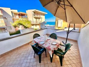 a table and chairs on a balcony with an umbrella at MARZIO - appartamenti con terrazzo, posto auto e spiaggia in Marcelli