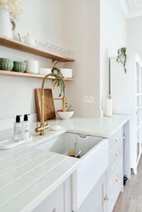 a kitchen with white cabinets and a sink at Driftwood House in Bournemouth