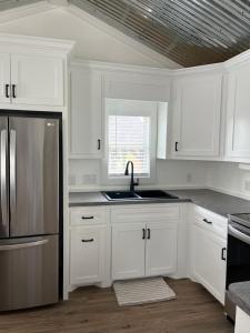 a kitchen with white cabinets and a stainless steel refrigerator at Cozy Cabin in Brazoria