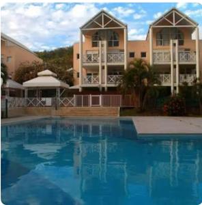 a large swimming pool in front of a building at Spacieux appartement avec terrasse et piscine au Diamant in Le Diamant