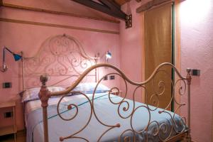 a bed in a pink bedroom with a metal bed frame at Ca da la Butina in Mergozzo +11 photos