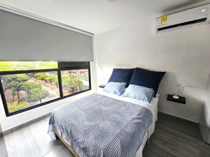 a bedroom with a bed with blue pillows and a window at Apartaestudio Moderno Miró in Cali +19 photos