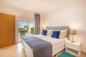 a bedroom with a large bed with blue pillows at NAU Salema Beach Village in Salema