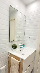 a white bathroom with a sink and a mirror at Piso Mariña in Marín