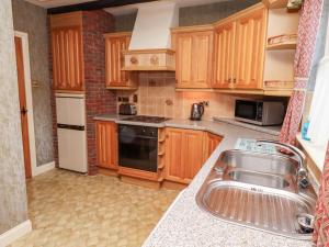 a kitchen with wooden cabinets and a sink at Foxglove Covet in Wooler