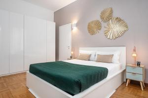 a white bedroom with a large bed with a green blanket at Classbnb - Two apartments 400 meters from the Duomo in Milan