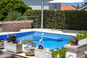 una piscina con piante in vaso e ombrellone di Ferienwohnung für 6 Personen ca 74 qm in Sveti Vid-Miholjice, Kvarner Bucht Krk a Sveti Vid-Miholjice