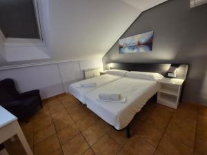 a bedroom with a large white bed and a chair at Hotel Tierra de Garnacha in Borja