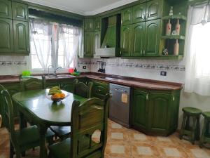 - une cuisine avec des placards verts et une table avec un bol de fruits dans l'établissement Casa de Campo Hiurma, à Triquivijate