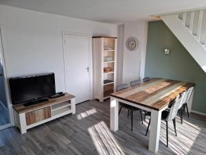 a living room with a table and a tv at Appartement met 3 slaapkamers vlakbij strand en centrum in Zoutelande