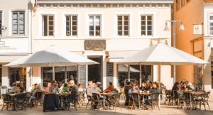 a group of people sitting at tables under umbrellas at Amalie Genusskult in Speyer