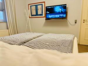 Un dormitorio con una cama con un televisor en la pared. en Meer-Lust-Sylt family and friends - 2025 refreshed, en Westerland