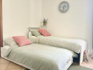 two beds in a room with a clock on the wall at ROSMARINO - Comodità e tranquillità con Giardino e Parcheggio in Imperia +23 photos