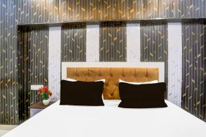 a bedroom with a white bed with black pillows at Super Hotel O Radha kunj By Namasya Retreat International in Prayagraj