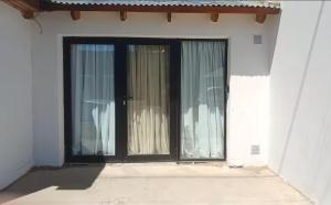 a door with two windows in a white building at Estudio con calefacción central, a 1 cuadra centro in El Calafate