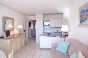 Una sala de estar con un sofá y una cocina. en Le Lavandou résidence les Mandariniers, en Le Lavandou 1 foto más