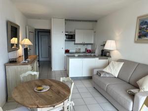 Una sala de estar con un sofá y una mesa y una cocina. en Le Lavandou résidence les Mandariniers, en Le Lavandou