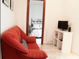 una sala de estar con una silla roja frente a un espejo en Fan Flat Rosaleda, en Málaga