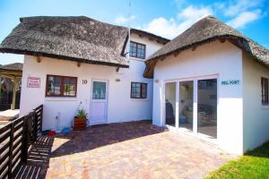 a small white house with a thatched roof at Cozy home 2 mins from the beach in Marina Glades +4 photos