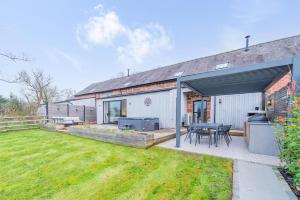 a house with a patio with a table and a grill at Tackroom Great Ness Shrewsbury in Great Ness
