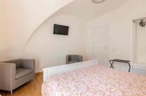 a bedroom with a bed and a chair and a television at San Martino House al Duomo in Catania