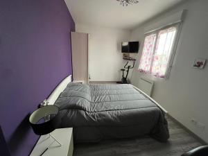 una camera da letto con un letto e una parete viola di À quatre Chez lulu a Riom