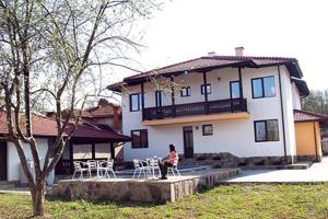 a person sitting in a chair in front of a house at DE-YAN Guest House in Oreshak