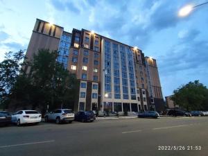 a large building with cars parked in a parking lot at 2х комнатная квартира ЖК Арман in Kokshetau