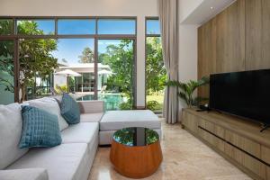 Il comprend un salon doté d'un canapé blanc et d'une télévision à écran plat. dans l'établissement Luxury Villa in heart of Bang Tao! Villa BEAM, à Laguna Phuket