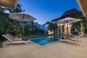 une villa avec une piscine, 2 chaises et des parasols dans l'établissement Luxury Villa in heart of Bang Tao! Villa BEAM, à Laguna Phuket
