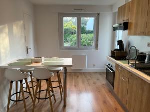 Una cocina con una mesa y algunas sillas y una ventana. en Le 102 - appart-sympa - T2, patio, jardin et cave - Larmor-Plage, en Larmor-Plage