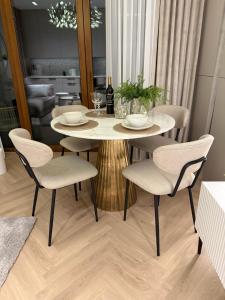 a dining room table with chairs and a table with a bottle of wine at Apartament Pod Żaglami 2 in Sława