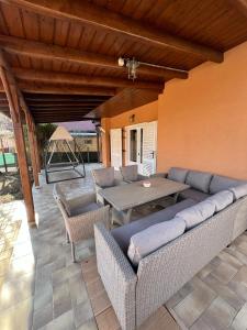 a patio with a couch and a table and chairs at Izabella Vendégház in Balatonszárszó