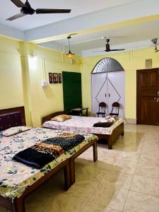 una camera con due letti e una porta con finestra di Heritage Inn Homestay Sivsagar a Sibsāgar